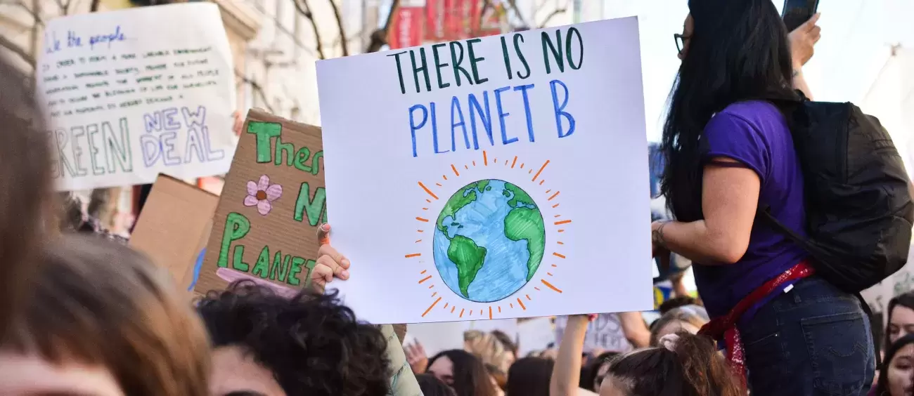 group of people protesting holding signs that say There is no Planet B