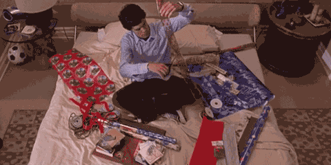 person surrounded by wrapping paper cuts off a piece