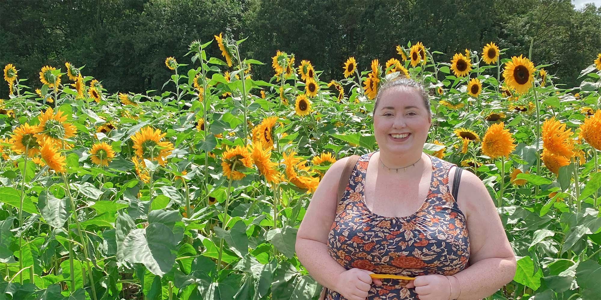 Lexie Manion stands smiling in a field of sunflowers
