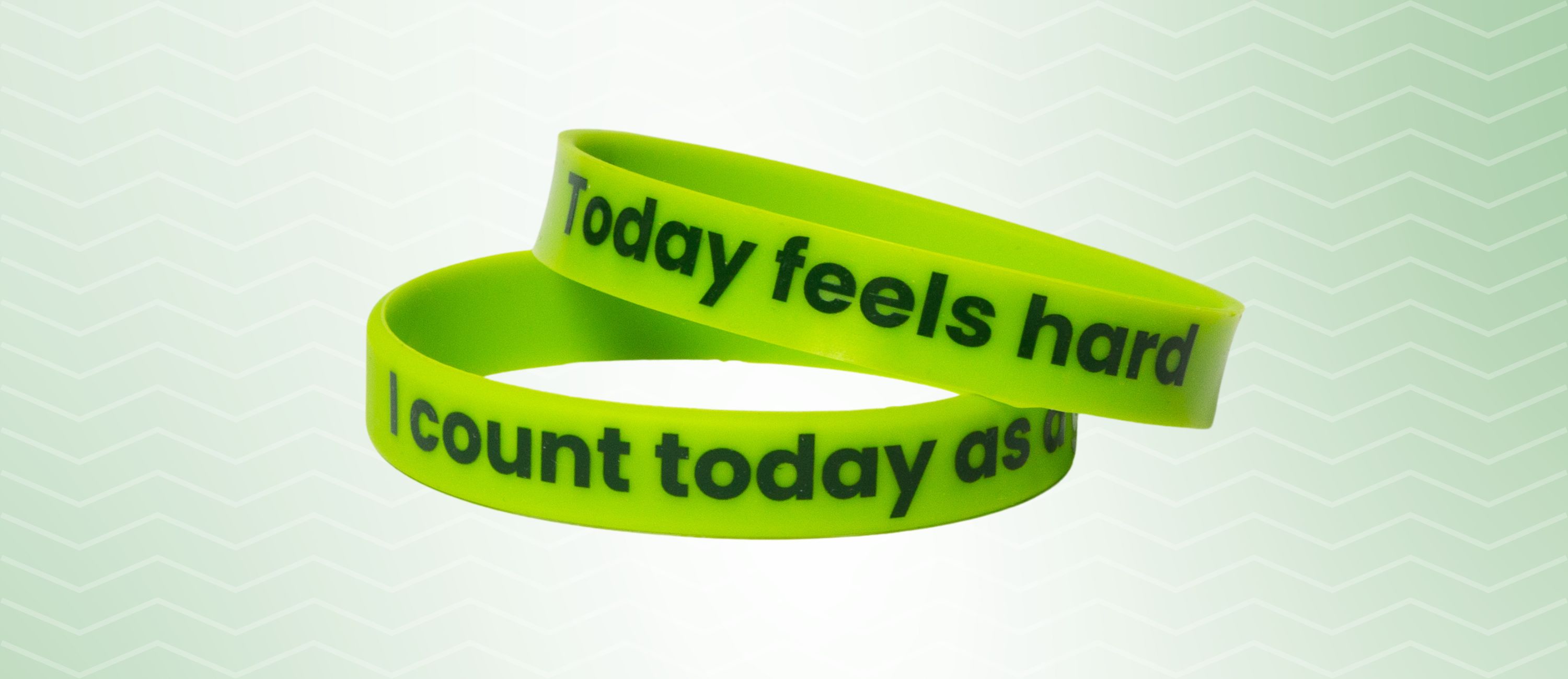 Two similar bracelets stacked on top of each other, one says Today feels hard, other says I count today as a good day