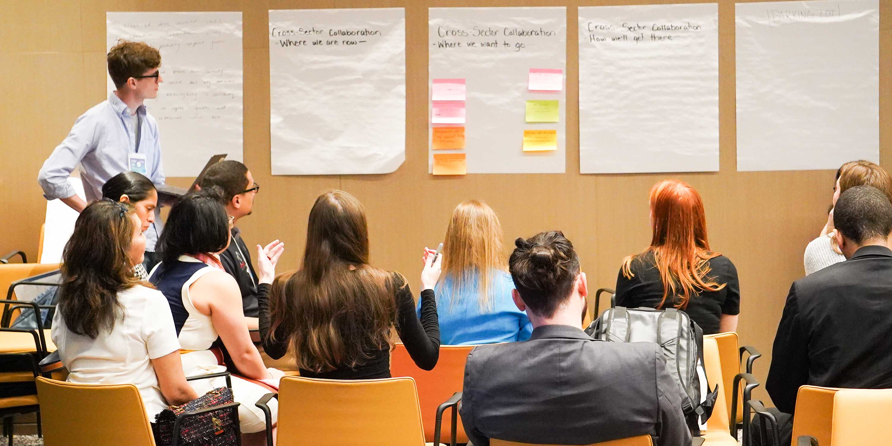 Young people brainstorm and write on large pieces of paper during the design sprint.