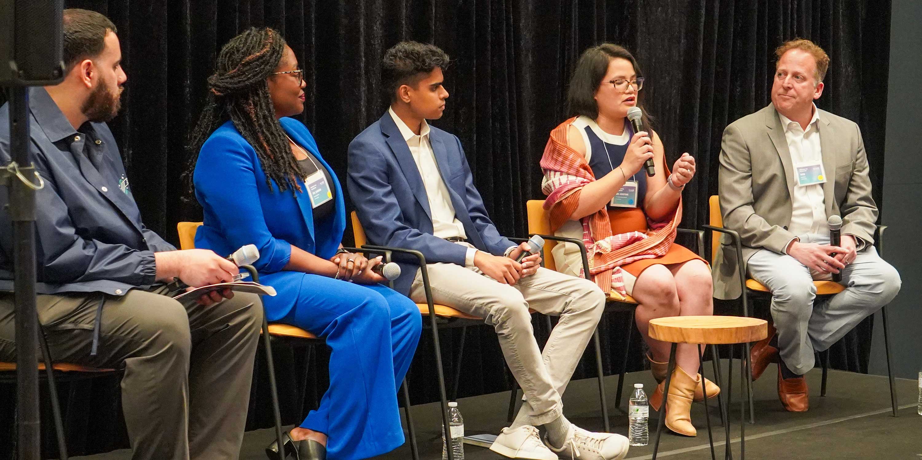 A panel of panelists speak on stage at Breaking the Algorithm