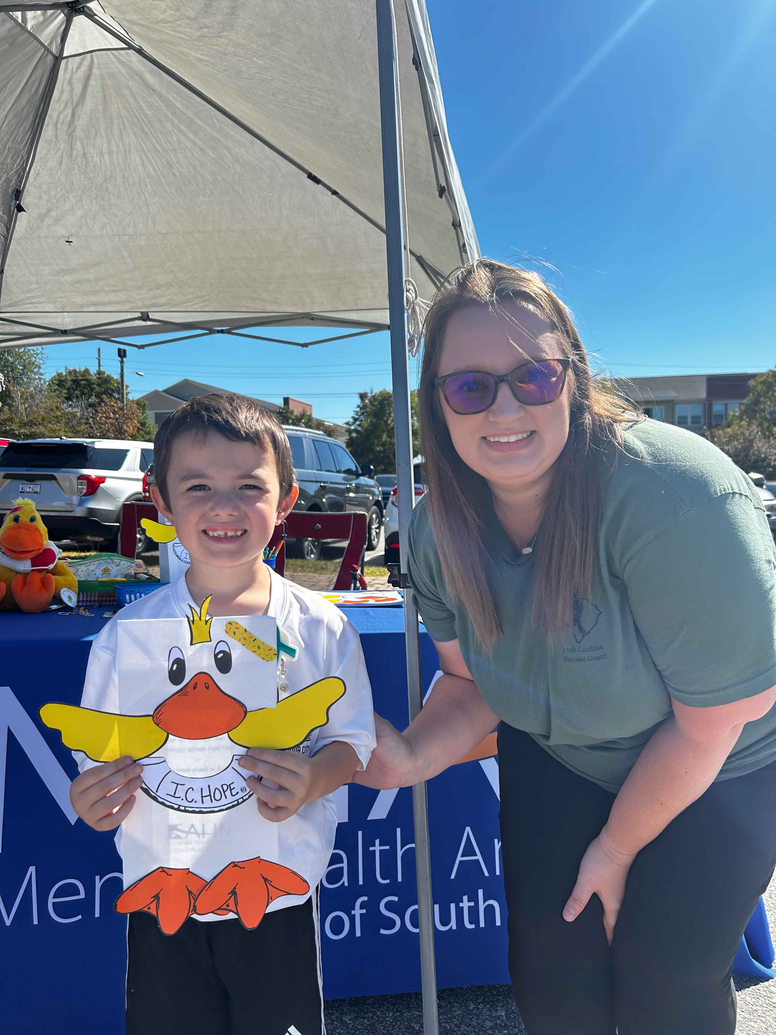 Mom and son hold an IC Hope duck paper bag puppet