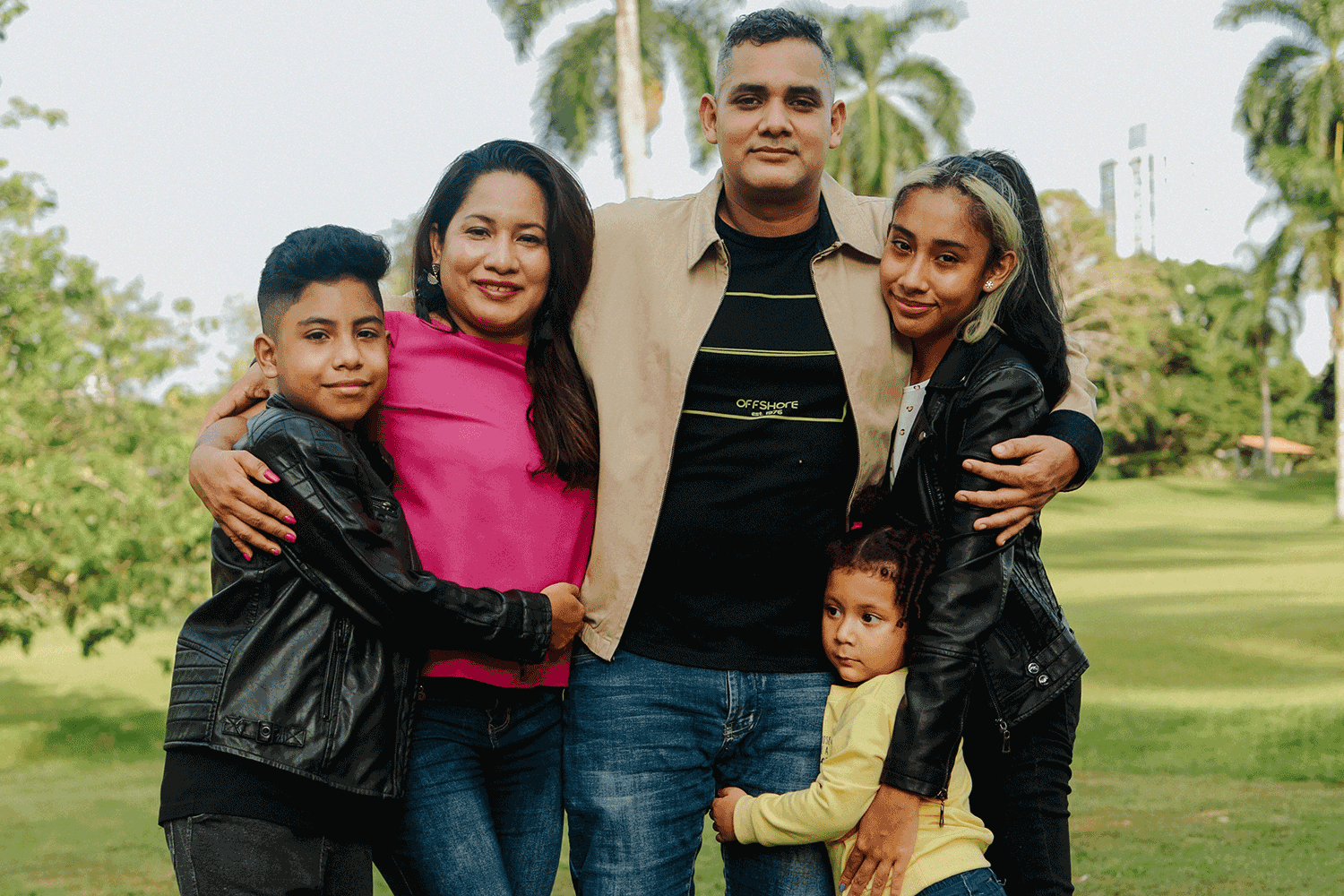 Latino family stands with arms around each other