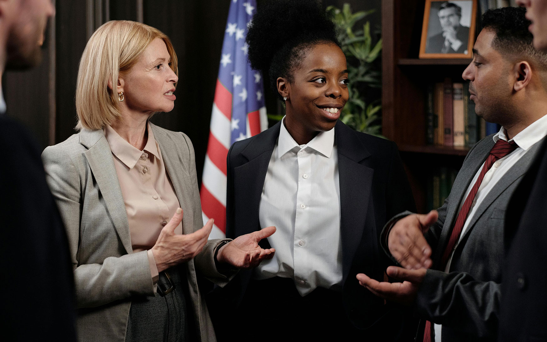 group of people in suits talk in front of an American flag