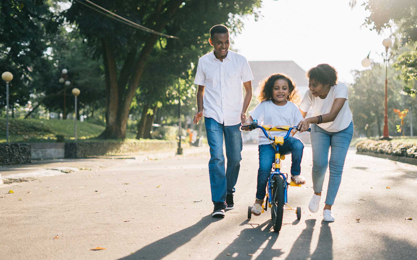 parents help child ride bike
