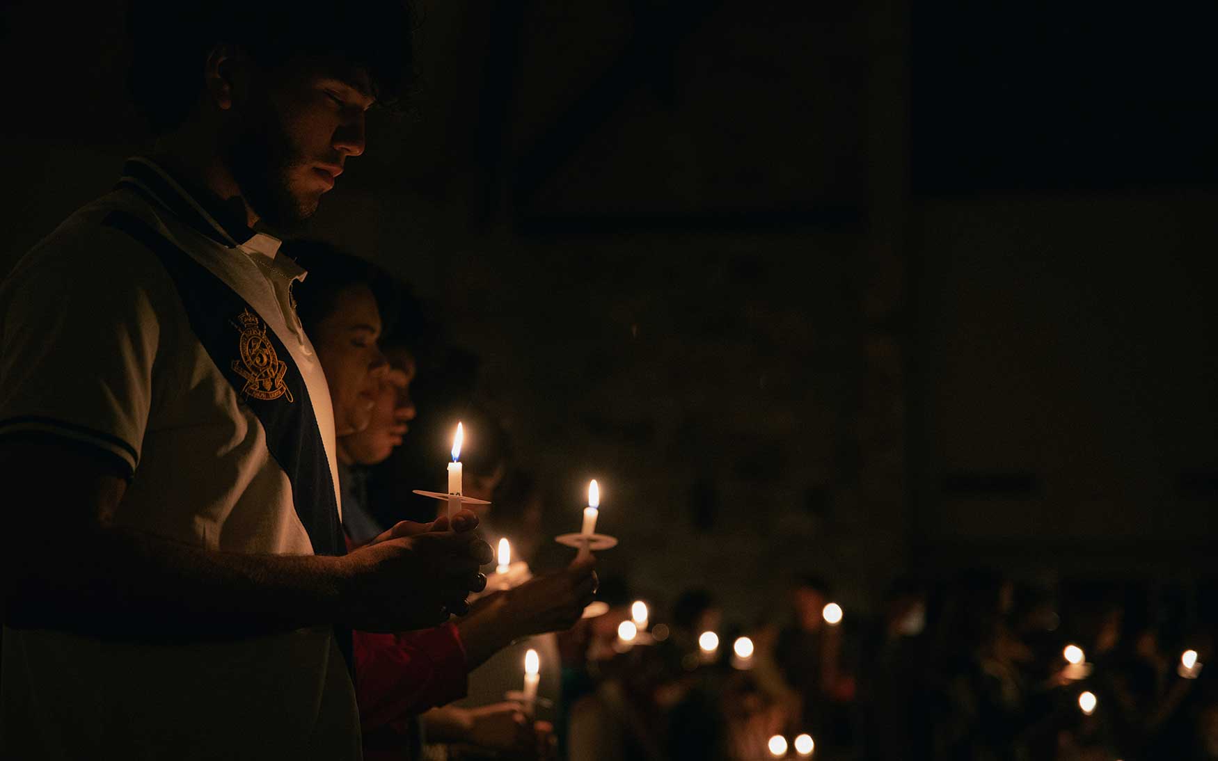 person stands holding candle at vigil