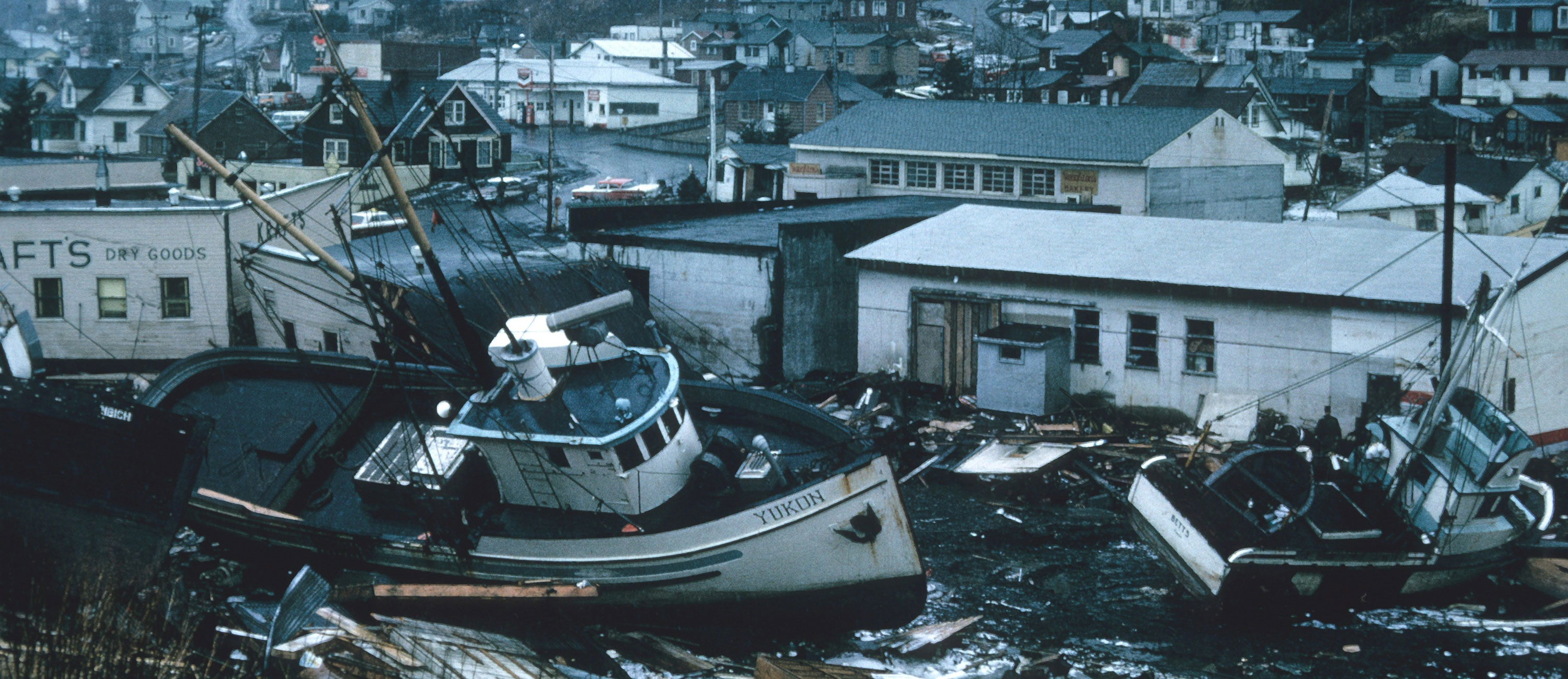 boats are wrecked on land near houses that are torn up from storms