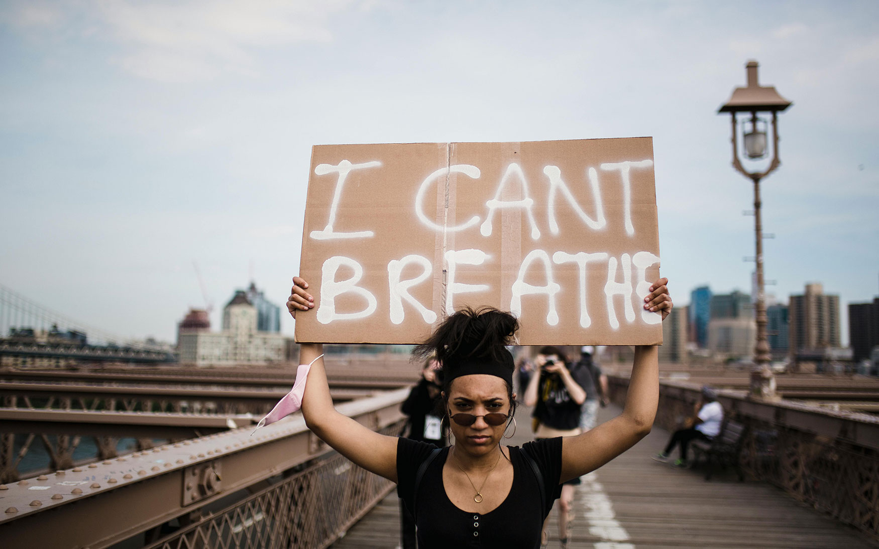 person marches holding sign saying I Can't Breathe