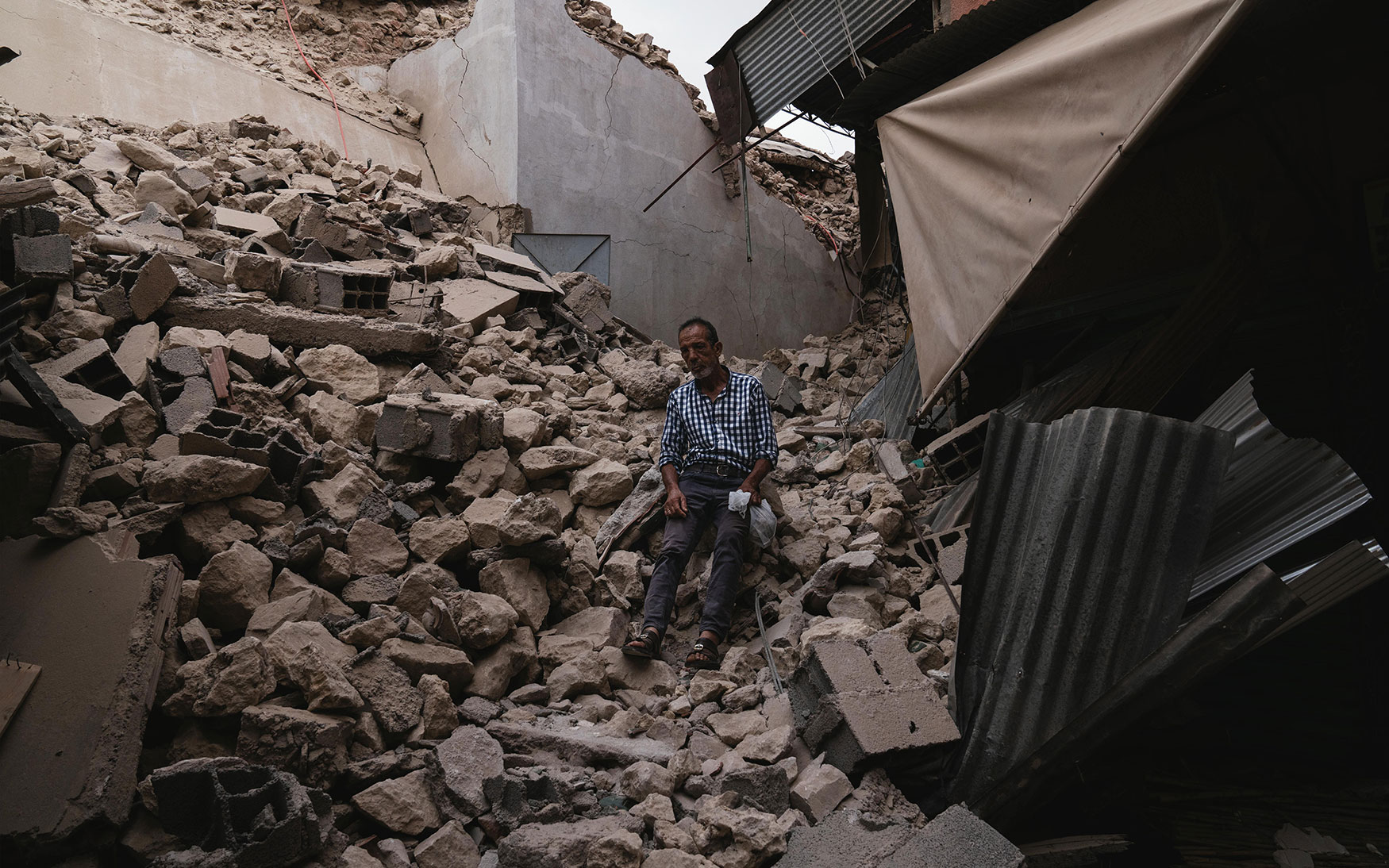 person sits amid rubble