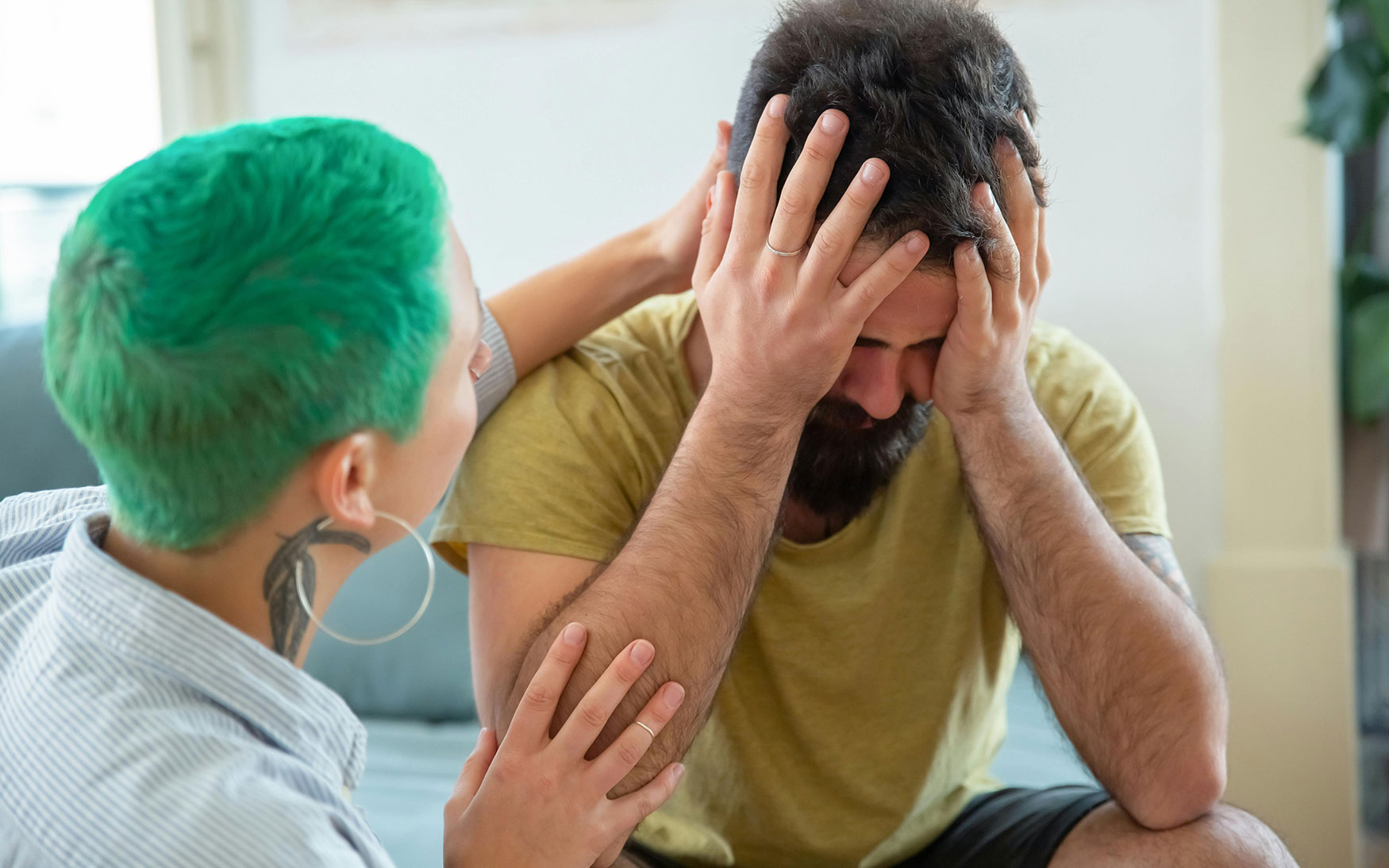 person with green hair consoles another person with their head in their hands