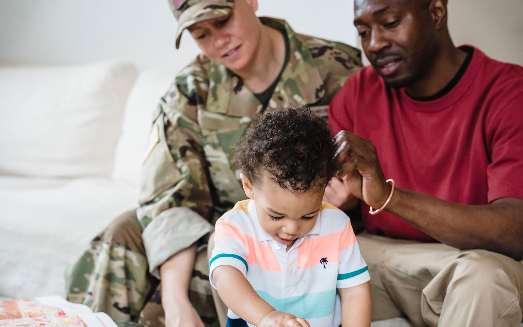 one parent in military uniform and one without sit with child