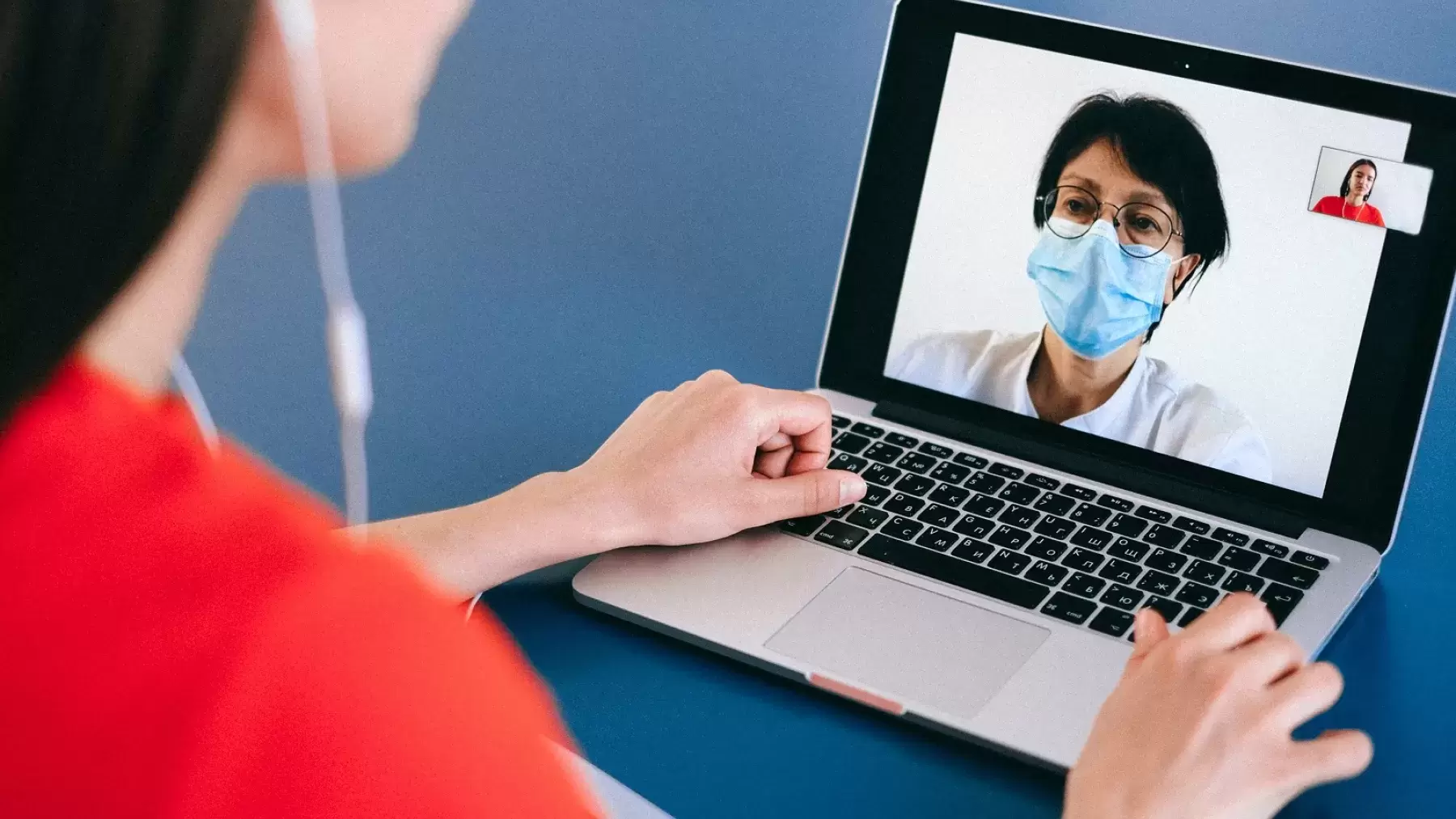 Person talking on a video call with a healthcare worker in a mask.