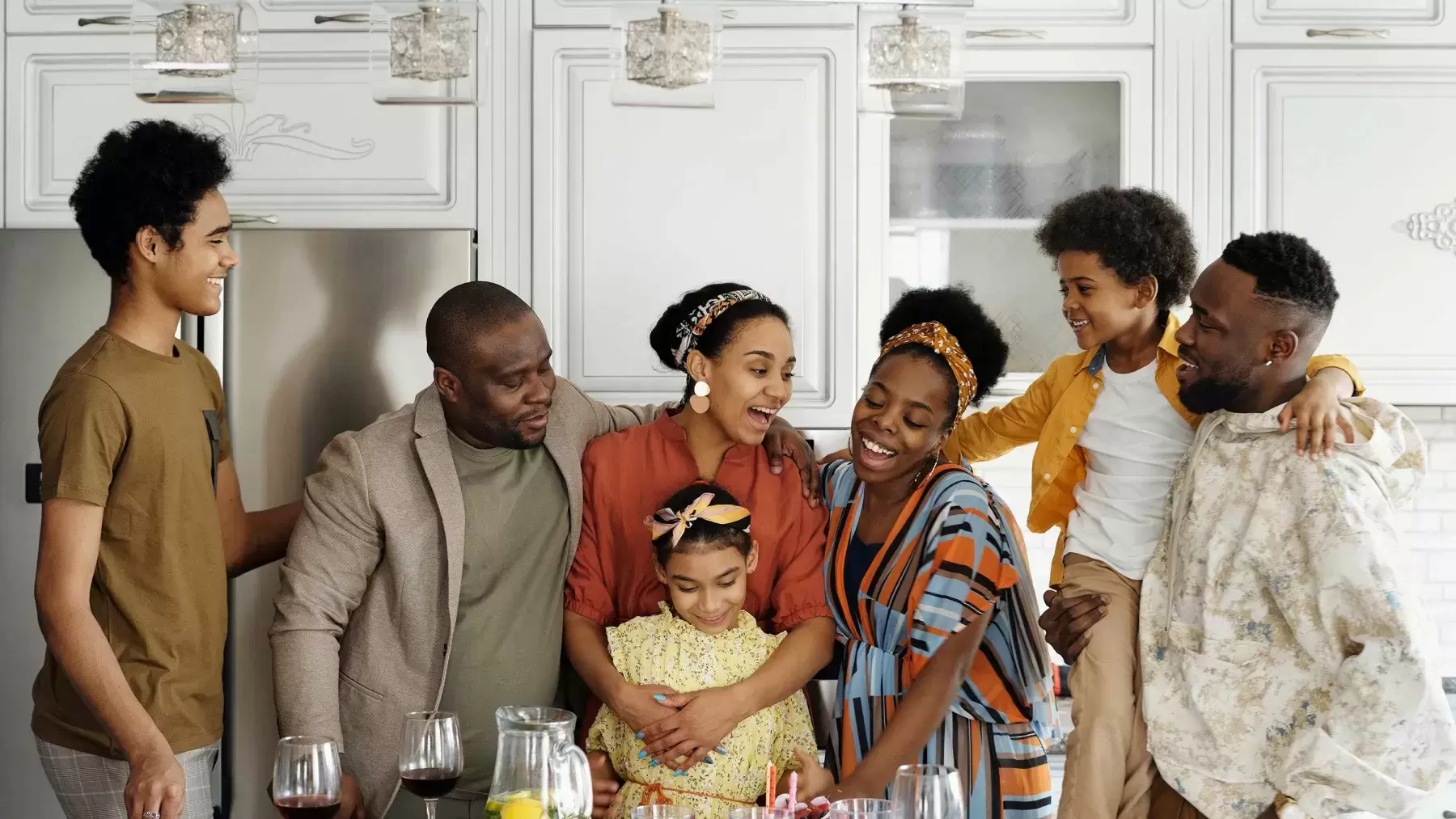 Black family stands around in kitchen smiling