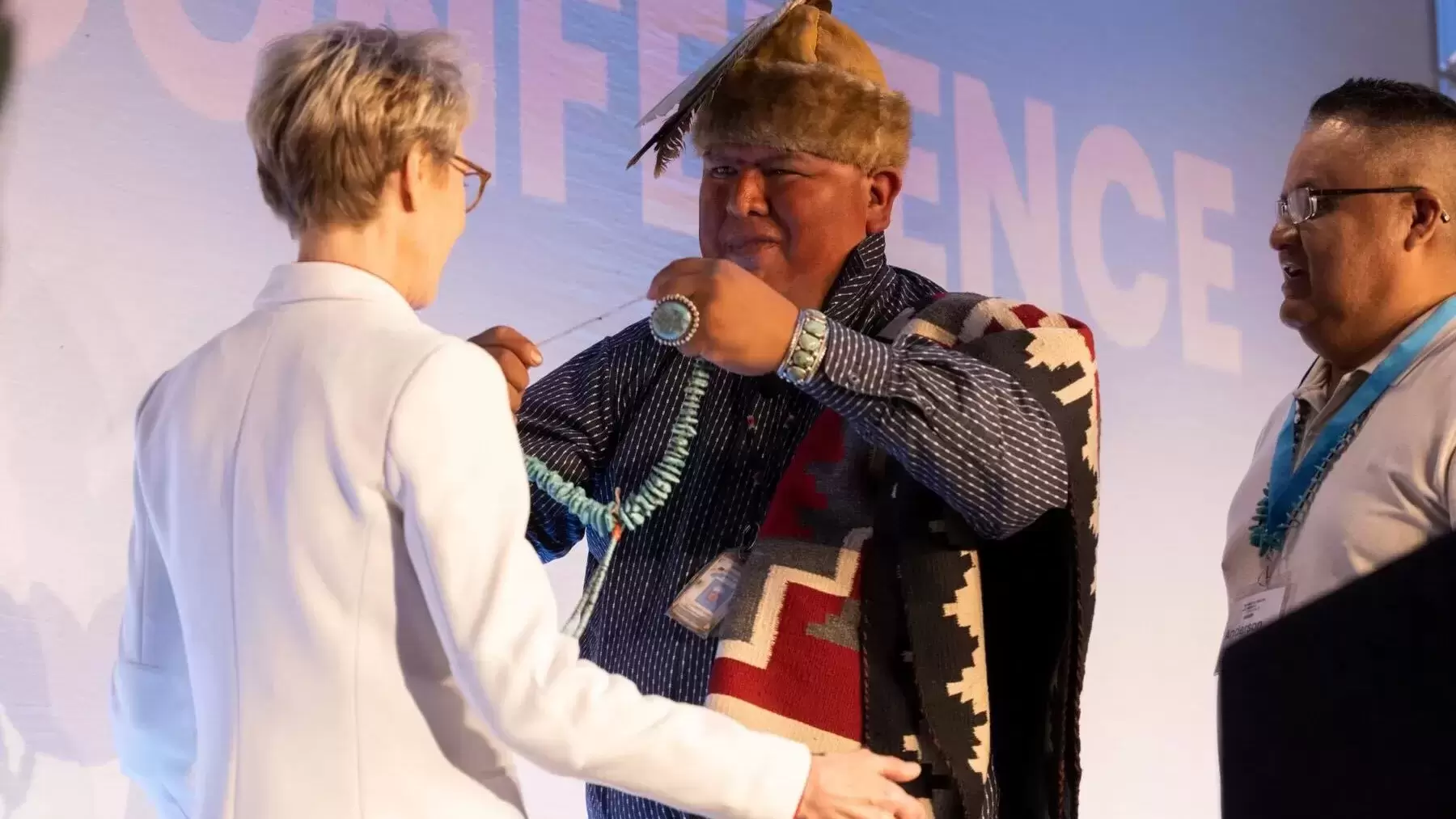 Mental Health America CEO and President Schroeder Stribling is presented with a necklace by medicine man Aaron D. Sam on conference stage. 