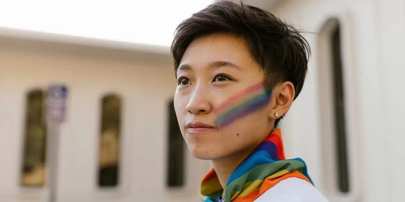 person with rainbow scarf on and rainbow painted on cheek