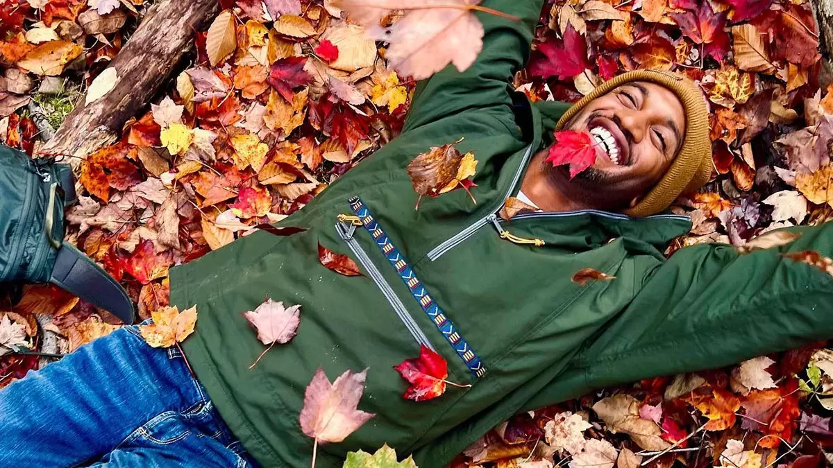 person lays on ground among falling leaves