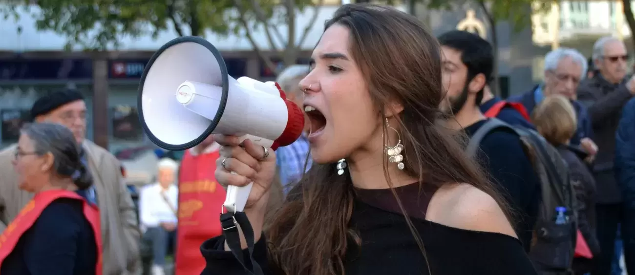 person stands in crowd yelling into megaphone