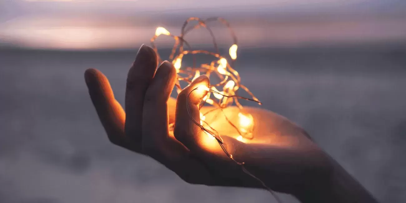 hand holds string of lights on a beach