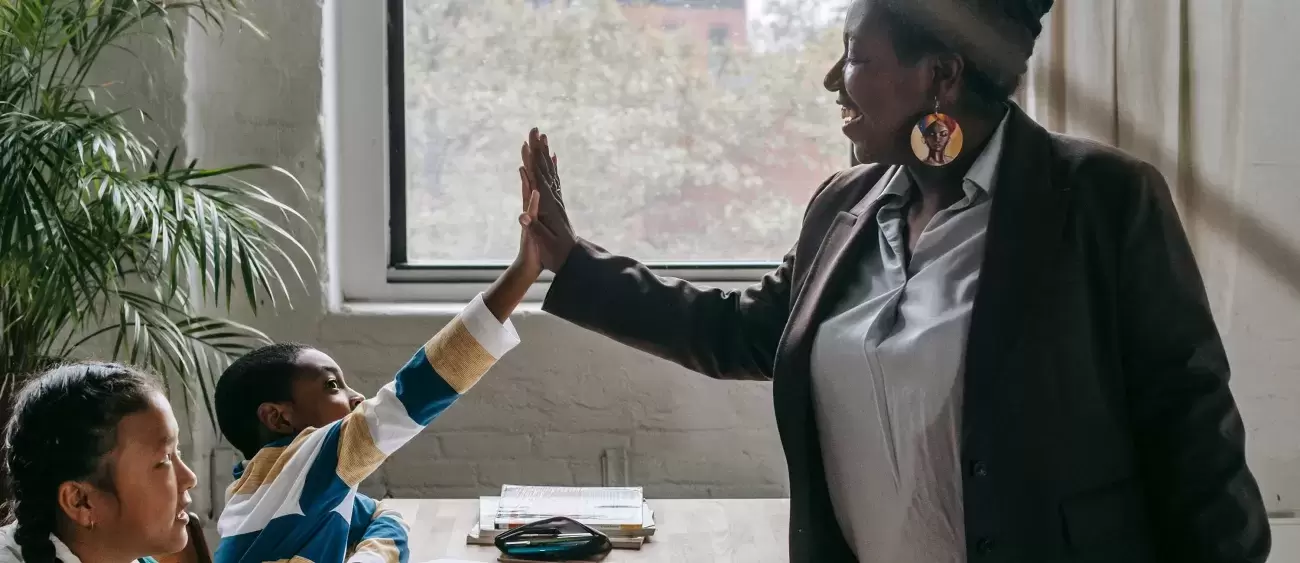 teacher high-fives student in classroom