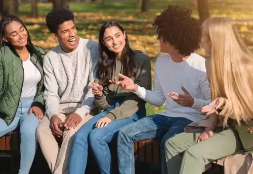 youth sit together on a bench talking animatedly and smiling