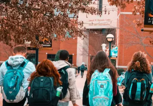 students walk on campus wearing backpacks
