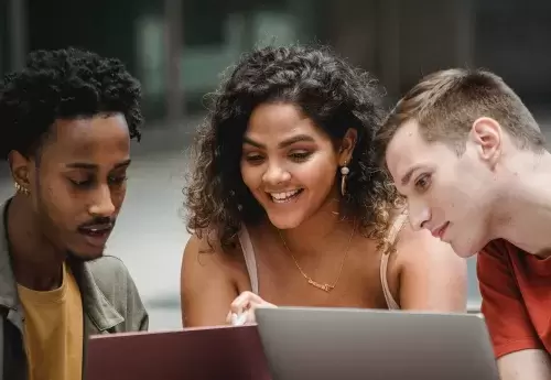 college students looking at a laptop and working together