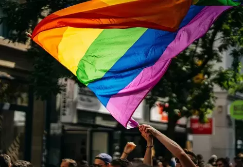 person waves rainbow LGBTQ+ pride flag