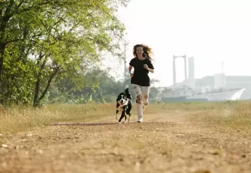 person runs with dog at their side