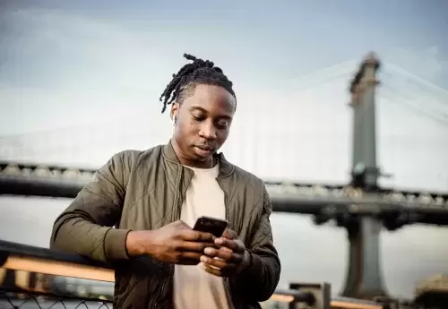 person stands on bridge while looking at phone