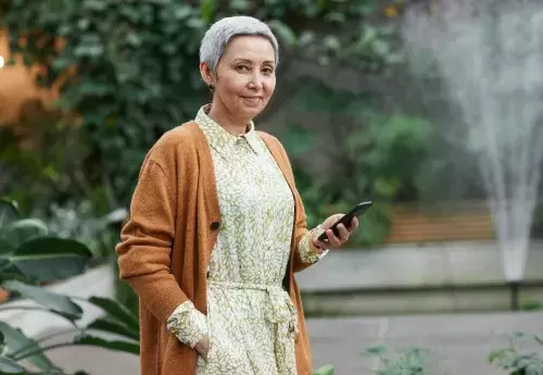 person in dress stands holding phone