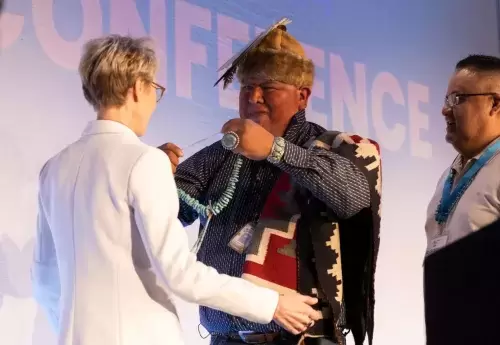 Mental Health America CEO and President Schroeder Stribling is presented with a necklace by medicine man Aaron D. Sam on conference stage. 