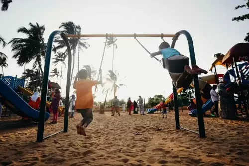 kids swinging on a playground with other people standing around