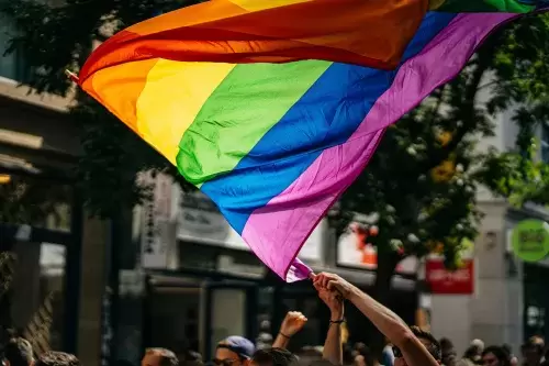 person waves rainbow LGBTQ+ pride flag