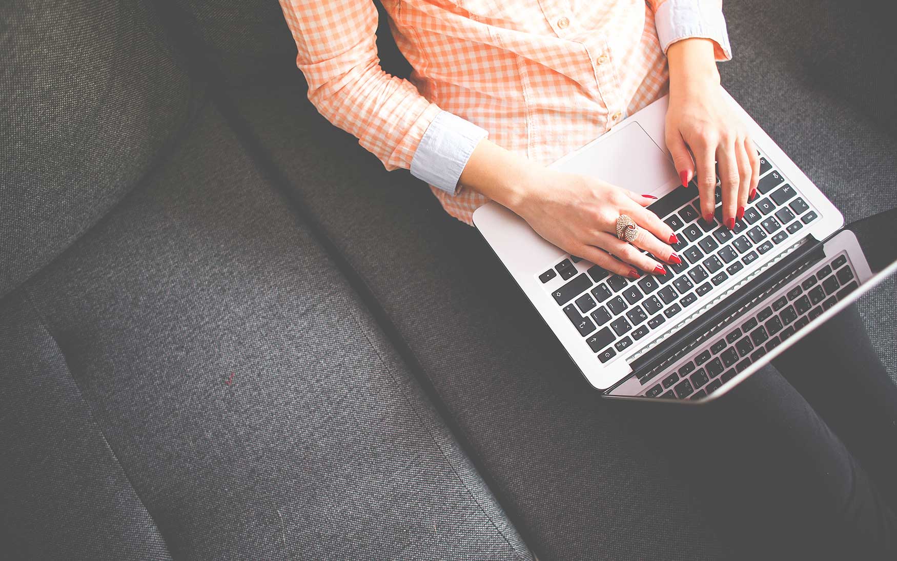 person sitting on couch typing on laptop