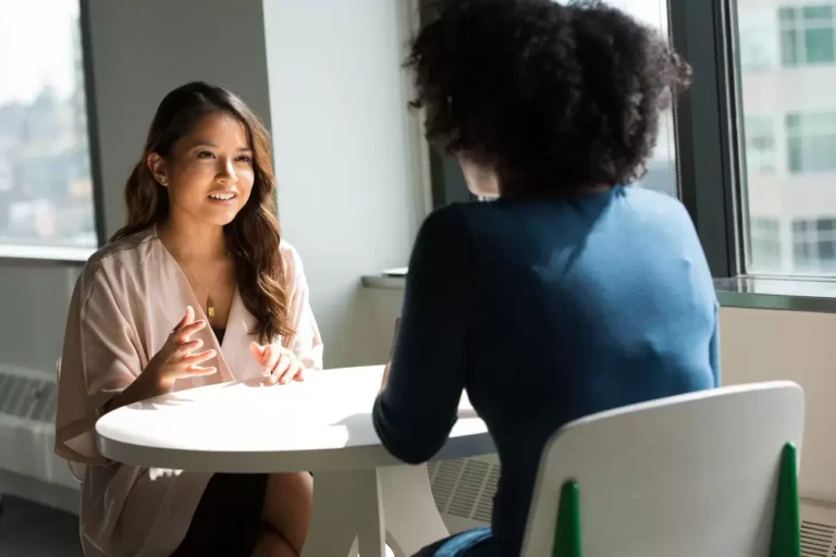 two people sit at table talking together