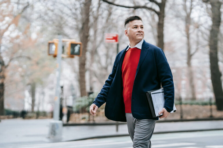 Man walking on a crosswalk in front of park