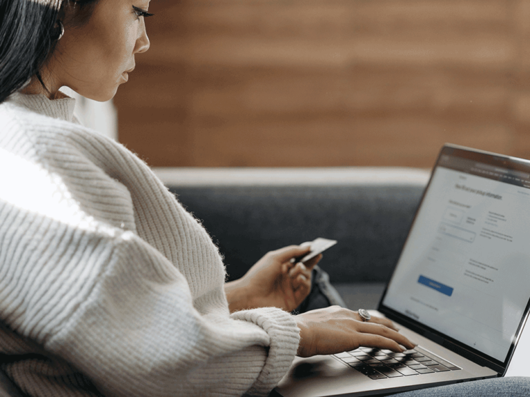 person looking at credit card while on laptop
