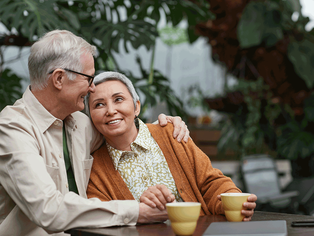 older couple snuggles while holding coffee