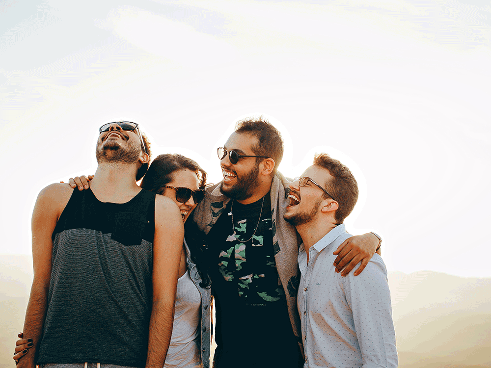 4 friends stand hugging and laughing together