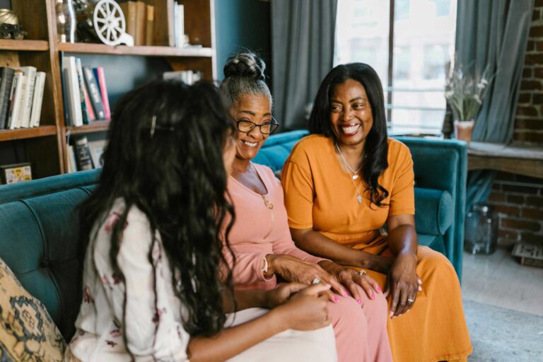 3 people sit on couch smiling and talking