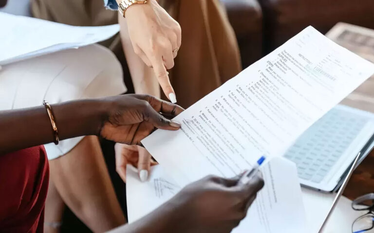 person holds report while another person points at report in their hands