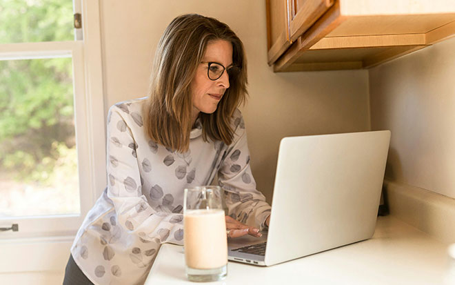 person standing at kitchen counter working on laptop