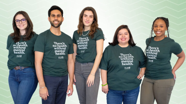 people stand all wearing green "Mental health is health" t-shirts
