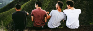 4 men sit with backs to us