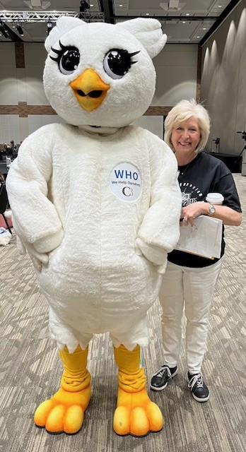 A person stands next to a large white owl mascot