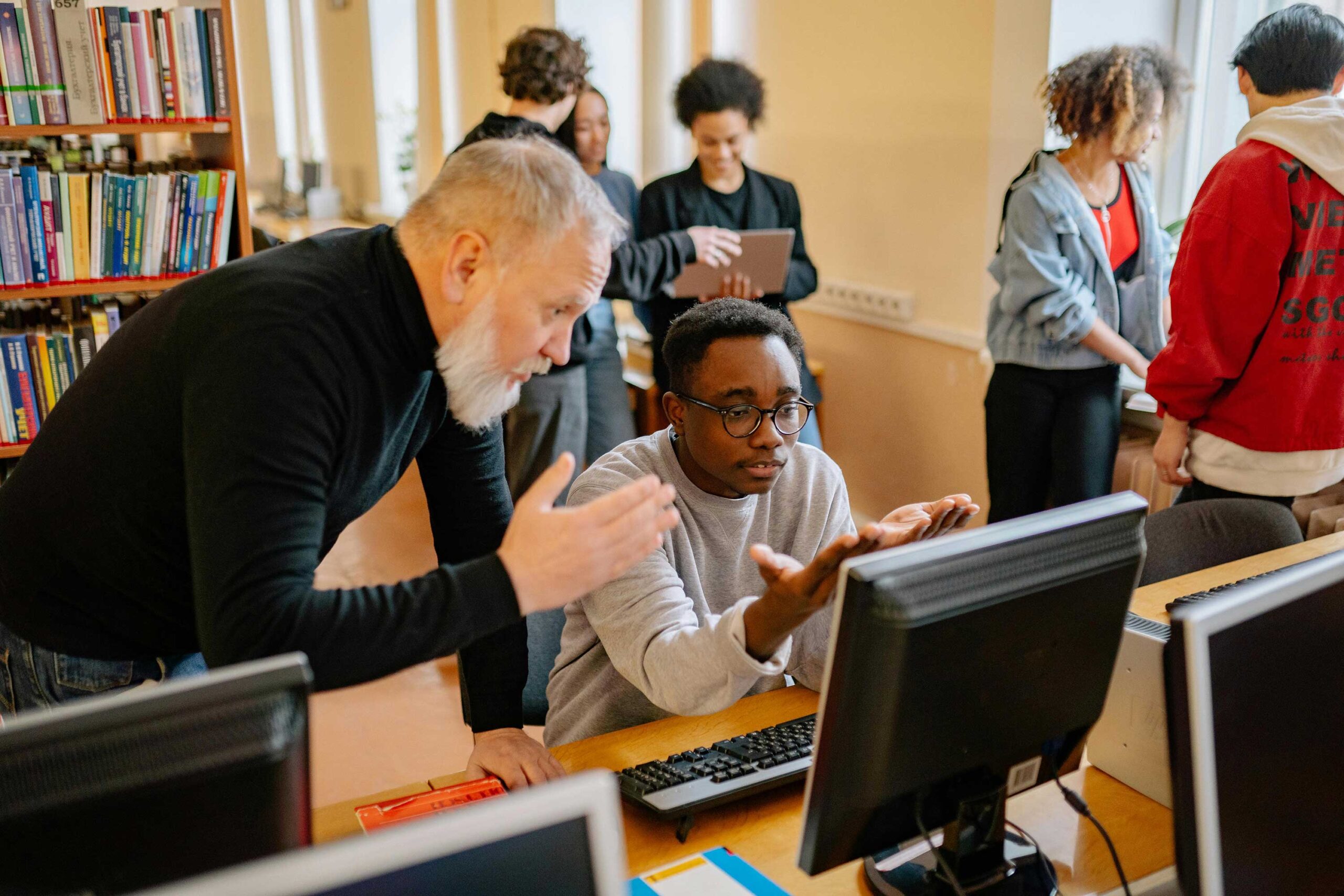 teacher helps student working on computer