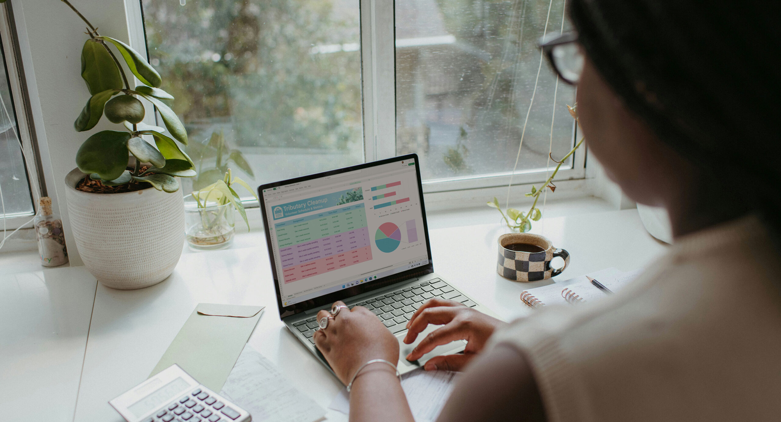 Person works at laptop on desk in front of window