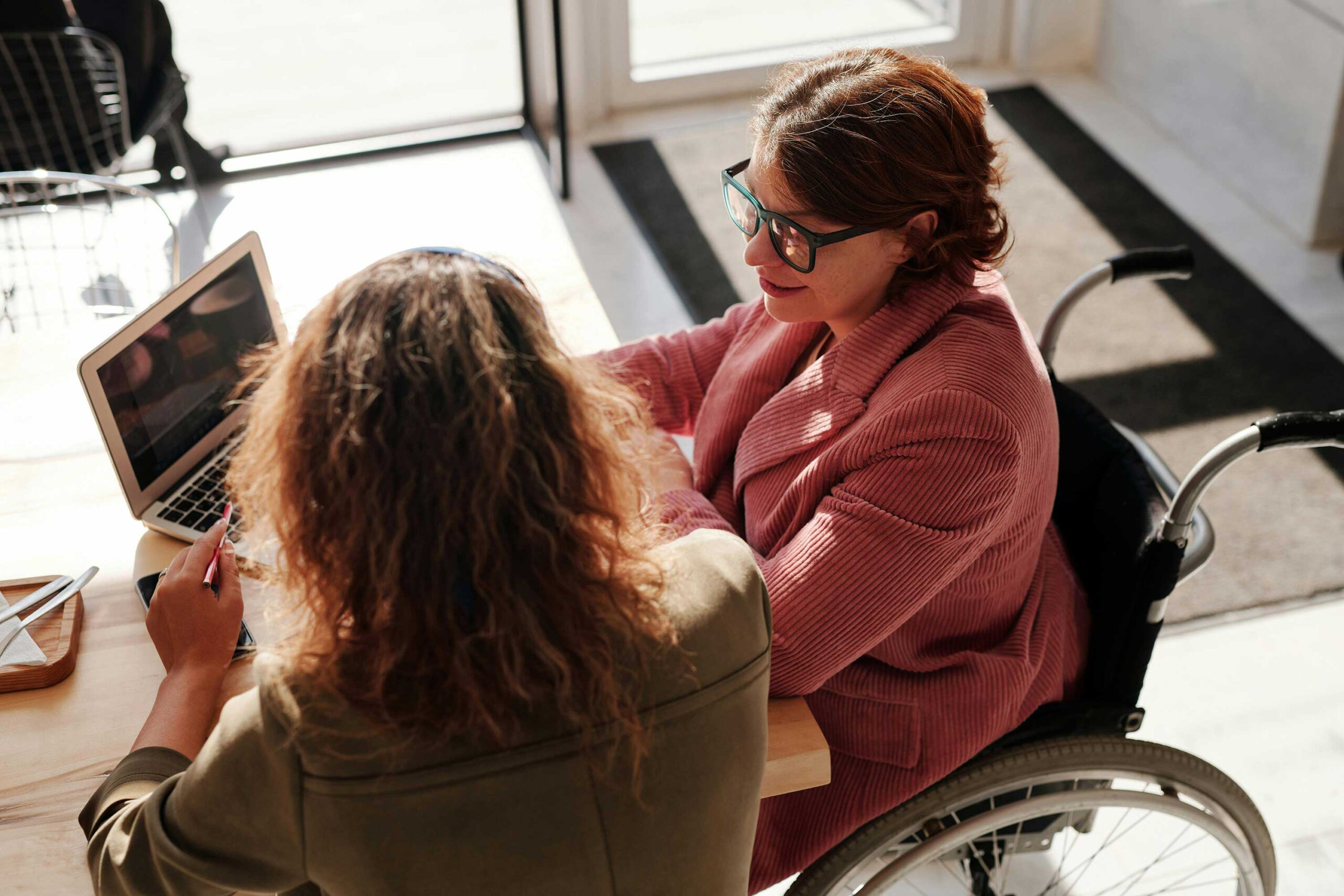2 people sit and look at a laptop together