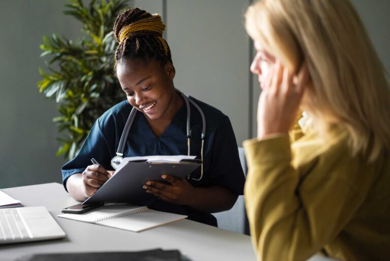 doctor fills out clipboard while talking with patient